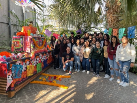 Spanish students pose for a picture in front of the ofrenda they created.